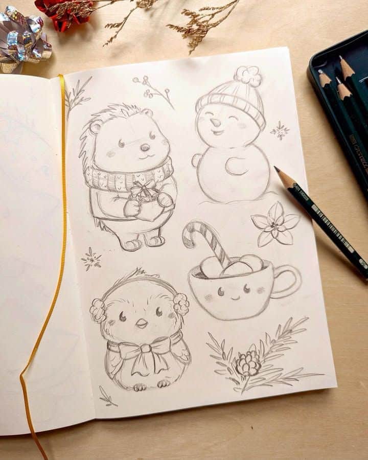 _ - 2025-12-30T114422995 Cute holiday sketches of a hedgehog, snowman, bird, and hot cocoa in a notebook, surrounded by pencils and festive decor. | Sky Rye Design Cute holiday sketches of a hedgehog, snowman, bird, and hot cocoa in a notebook, surrounded by pencils and festive decor.