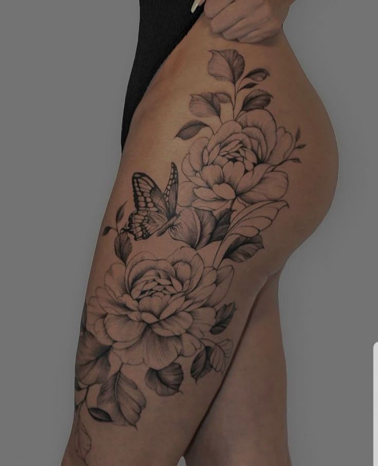 _ 21 Floral tattoo with roses and butterfly on thigh, showcasing intricate design and artistic shading on a gray background. | Sky Rye Design Floral tattoo with roses and butterfly on thigh, showcasing intricate design and artistic shading on a gray background.