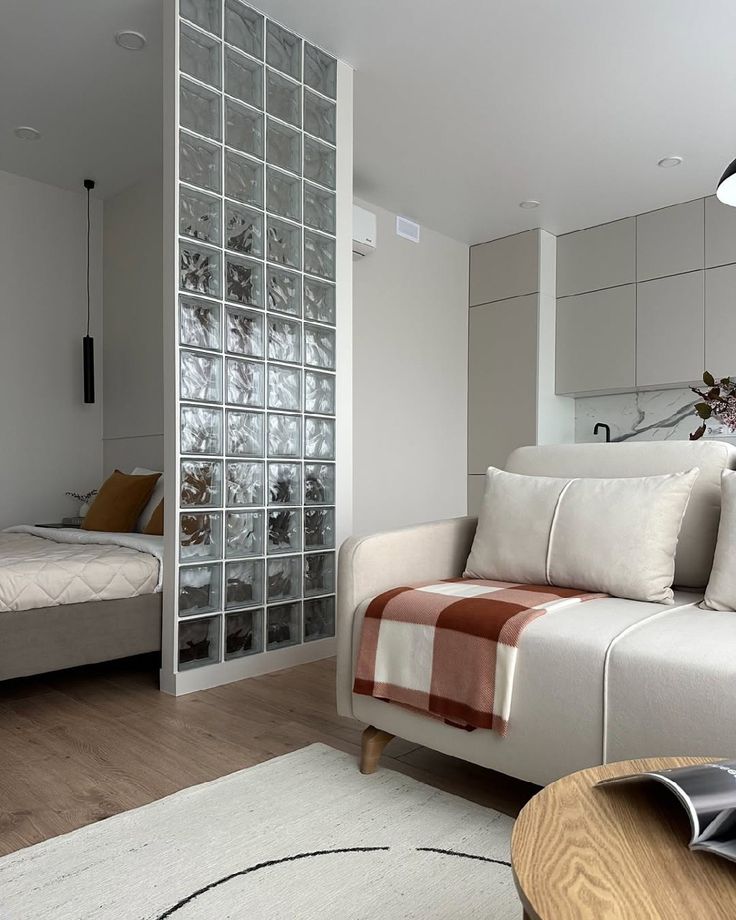 _ 22 Modern apartment interior with cozy beige sofa, plaid blanket, glass partition, and minimalist kitchen. Neutral tones and natural light. | Sky Rye Design Modern apartment interior with cozy beige sofa, plaid blanket, glass partition, and minimalist kitchen. Neutral tones and natural light.