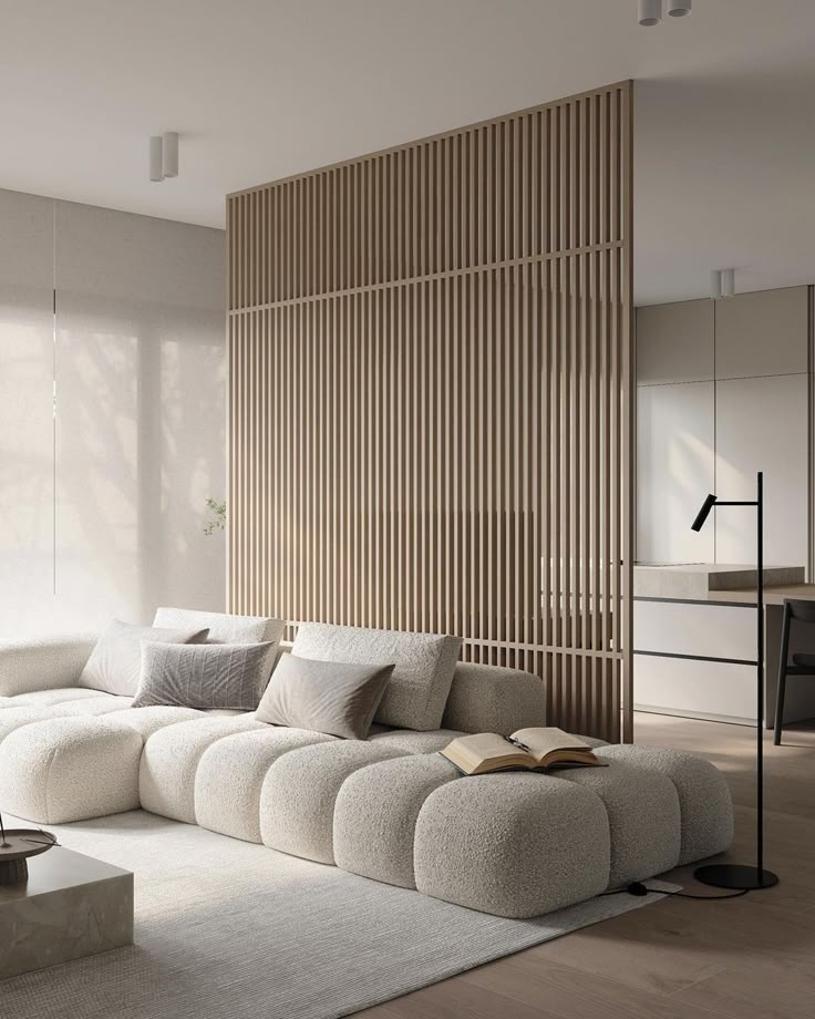 _ 24 Modern living room with cozy beige sectional sofa, wooden slat divider, plush cushions, and a minimalist floor lamp in natural lighting. | Sky Rye Design Modern living room with cozy beige sectional sofa, wooden slat divider, plush cushions, and a minimalist floor lamp in natural lighting.
