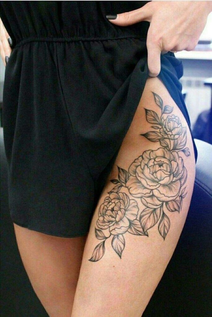 _ 25 Floral thigh tattoo with detailed roses and leaves on a woman's leg, revealed under a black dress. | Sky Rye Design Floral thigh tattoo with detailed roses and leaves on a woman's leg, revealed under a black dress.