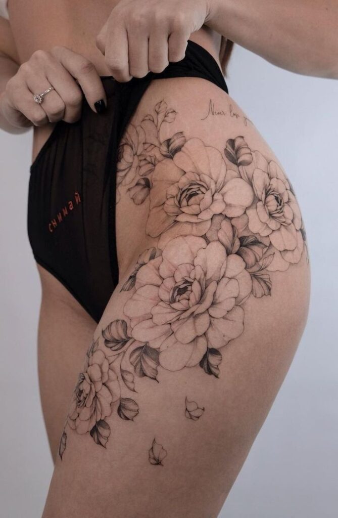 _ 26 Floral thigh tattoo design on woman showcasing detailed black and gray roses, emphasizing intricate artistry and body art expression. | Sky Rye Design Floral thigh tattoo design on woman showcasing detailed black and gray roses, emphasizing intricate artistry and body art expression.