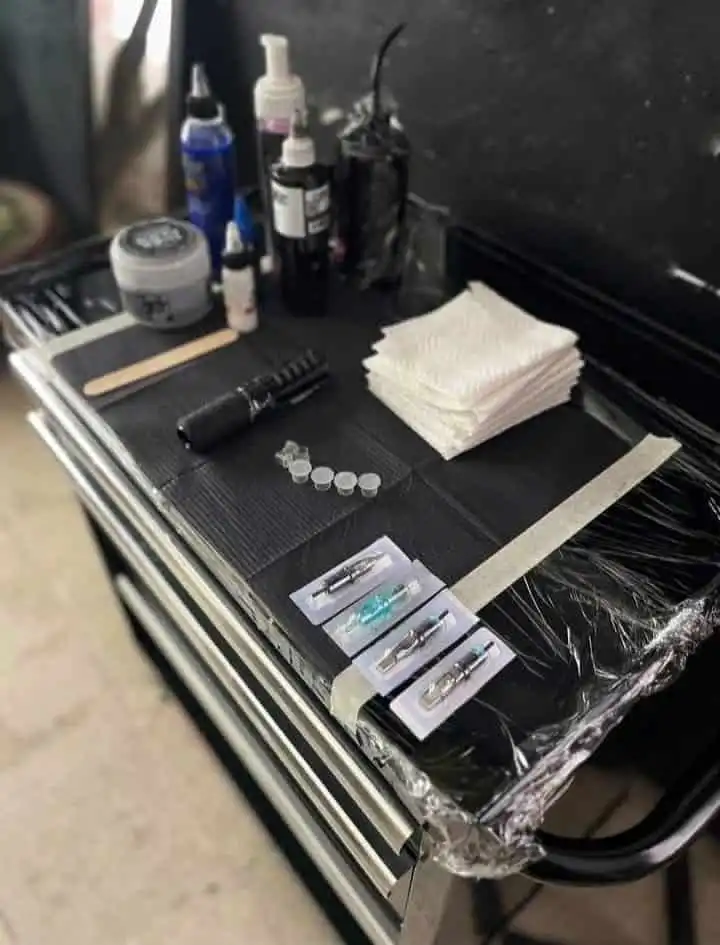 Tattoo artist's workstation with ink, needles, and supplies neatly arranged for tattooing.