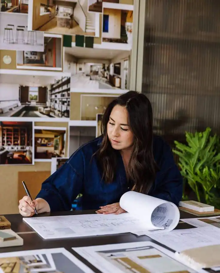 Architect reviewing blueprints at desk with design inspiration board in background. industrial design degree programs