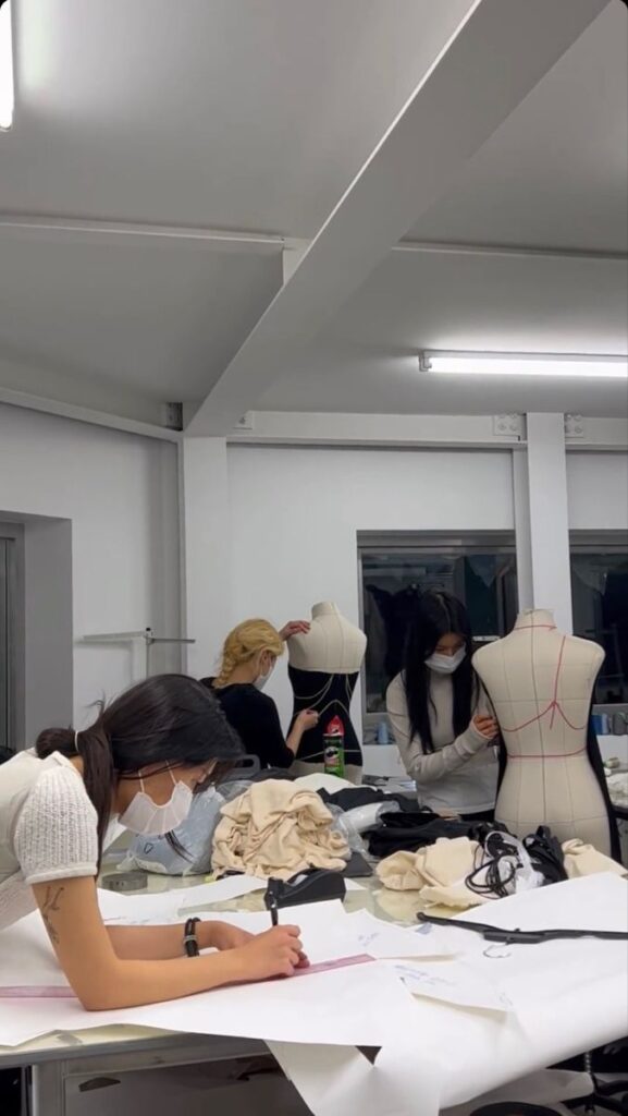 Fashion design students working on dress forms and sketches in a studio, honing their craft with dedication and creativity.