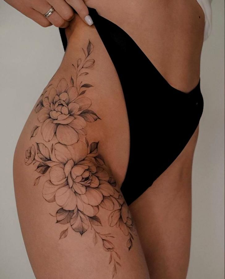 30 Elegant Thigh Tattoos To Level Up Your Sexiness And Charm Floral thigh tattoo in black ink, featuring detailed flowers and leaves, showcased on a woman's hip with black bikini bottom. | Sky Rye Design Floral thigh tattoo in black ink, featuring detailed flowers and leaves, showcased on a woman's hip with black bikini bottom.