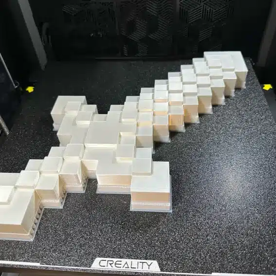 30e7f246a4c6aafb5d1356ebbe671ce4 3D-printed pixelated sword on Creality printer, resembling a video game weapon, showcasing intricate layered design. | Sky Rye Design 3D-printed pixelated sword on Creality printer, resembling a video game weapon, showcasing intricate layered design.