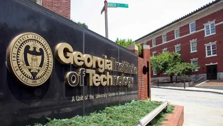 Sign for Georgia Institute of Technology near red brick building and greenery, conveying academic atmosphere.