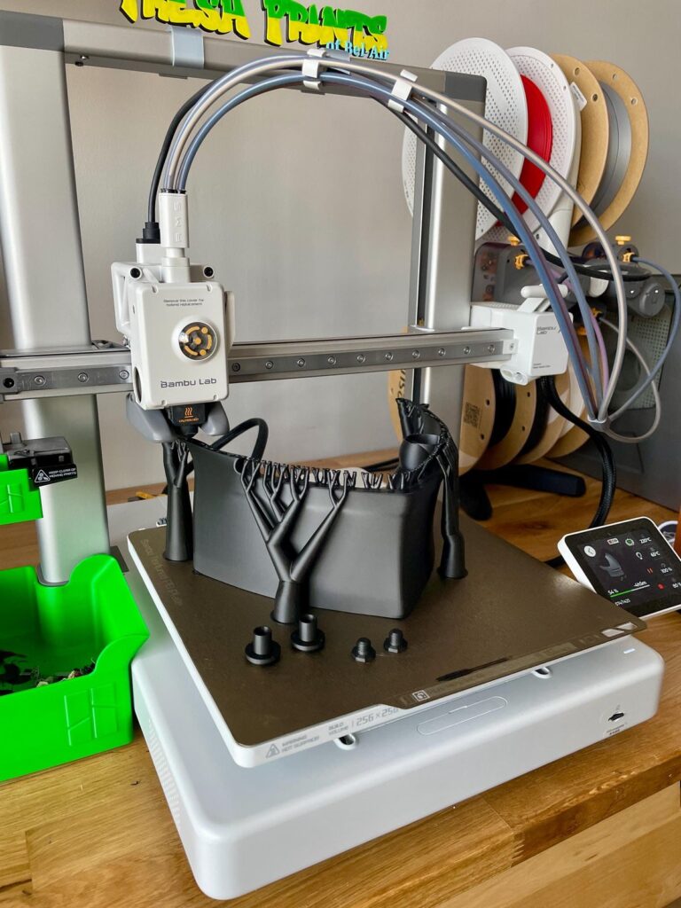 3D printer creating intricate black plastic structure with multiple spools in background, focusing on precision and technology.