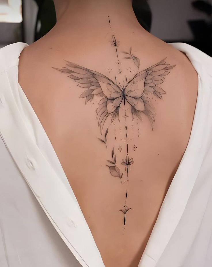 _ 39 Elegant butterfly back tattoo with floral details on woman in open-back white dress. | Sky Rye Design Elegant butterfly back tattoo with floral details on woman in open-back white dress.