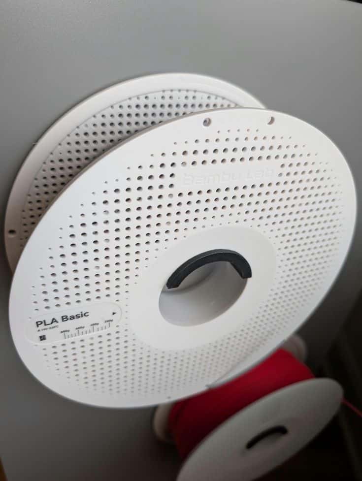 3D Printer Filament Wall Mounted Heavy Duty Filament Spool Holder Close-up of a white spool of PLA Basic 3D printing filament on a wall mount, highlighting brand and specifications. | Sky Rye Design Close-up of a white spool of PLA Basic 3D printing filament on a wall mount, highlighting brand and specifications.