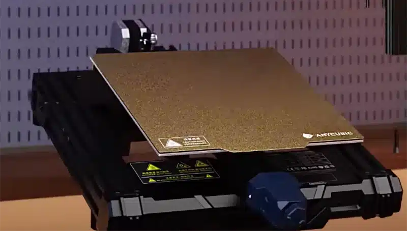 Close-up of an Anycubic 3D printer build plate in a workshop, showcasing its textured surface for enhanced printing adhesion.