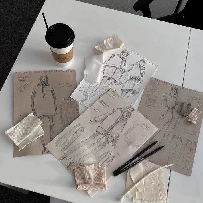 _ 4 Fashion design sketches and fabric samples on a table with a coffee cup, illustrating the creative process in clothing design. | Sky Rye Design Fashion design sketches and fabric samples on a table with a coffee cup, illustrating the creative process in clothing design.