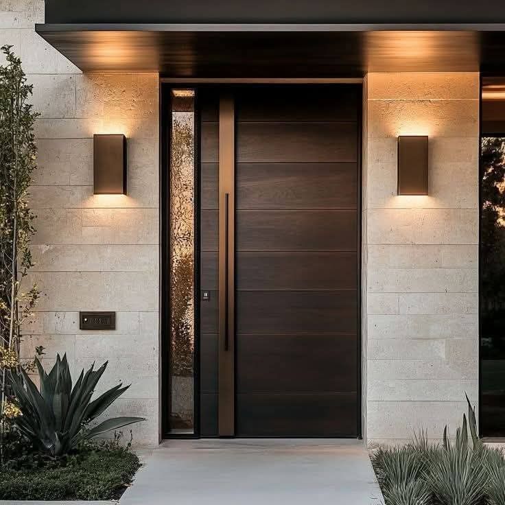 _ 4 Modern front door with elegant lights on a textured wall, framed by greenery. Stylish entrance of a contemporary home. | Sky Rye Design Modern front door with elegant lights on a textured wall, framed by greenery. Stylish entrance of a contemporary home.