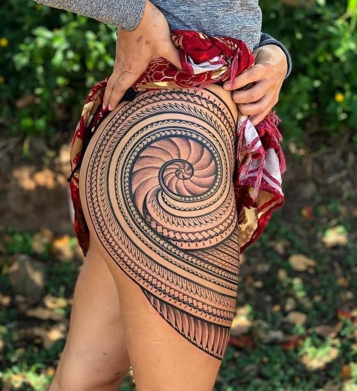 _ 4 Intricate spiral tattoo on a person's thigh with detailed patterns, set against a lush green background. | Sky Rye Design Intricate spiral tattoo on a person's thigh with detailed patterns, set against a lush green background.