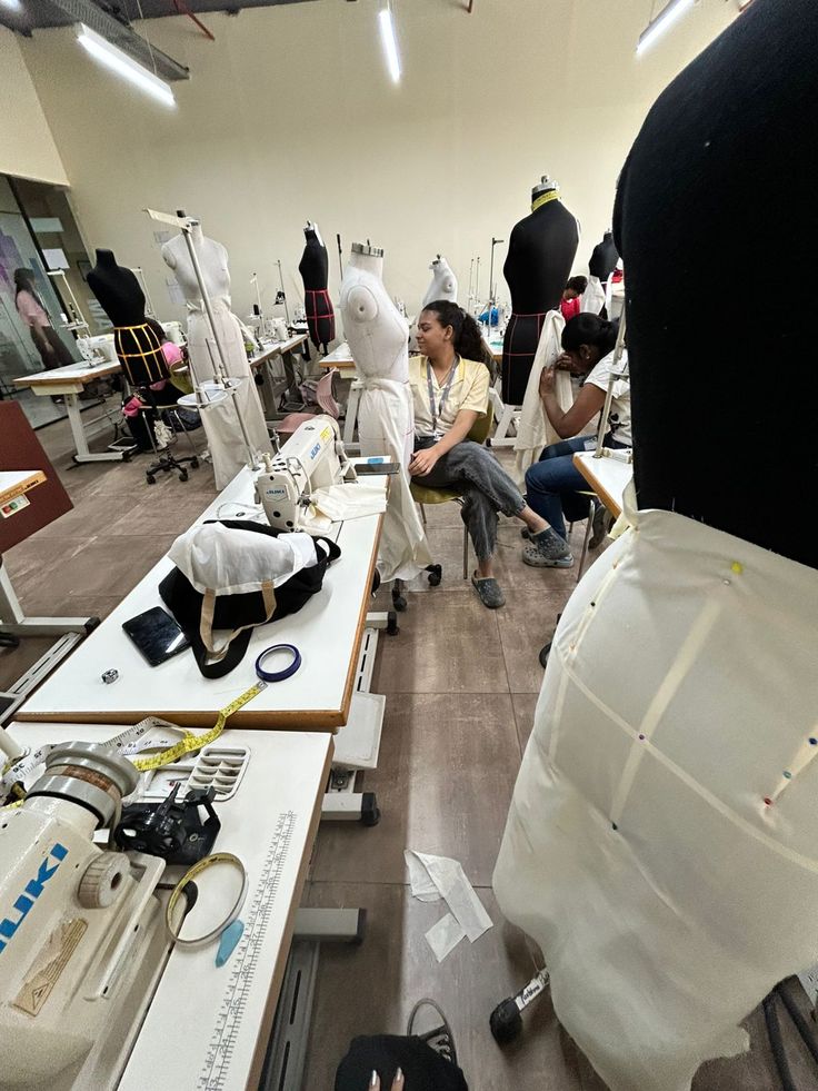 Fashion design students working in a classroom filled with mannequins and sewing machines, creating new garment designs.