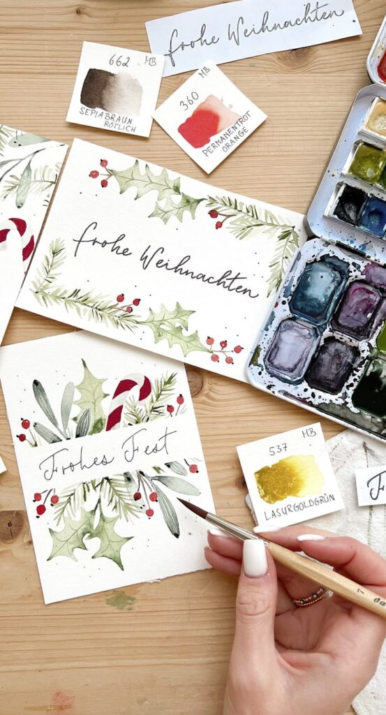 4 einfache Aquarell Weihnachtskarten malen Festtagszauber Hand-painted Christmas cards with holly and pine designs on a wooden table, featuring the text frohe Weihnachten and Frohes Fest. | Sky Rye Design Hand-painted Christmas cards with holly and pine designs on a wooden table, featuring the text frohe Weihnachten and Frohes Fest.