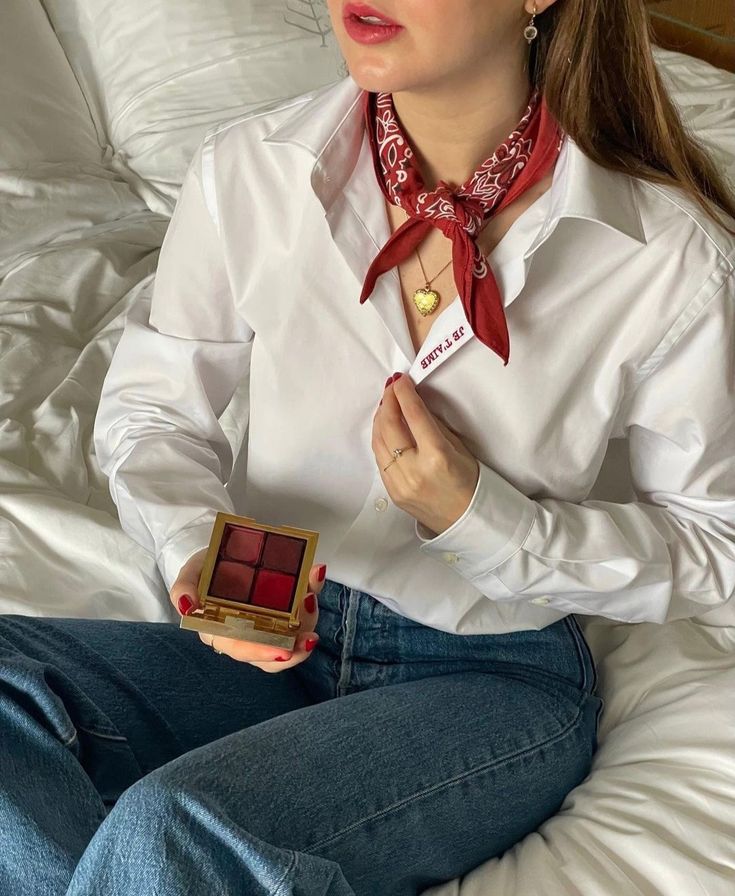 _ 43 Woman in white shirt and red bandana holding makeup palette, sitting on a bed. Casual style with jewelry and red nails. | Sky Rye Design Woman in white shirt and red bandana holding makeup palette, sitting on a bed. Casual style with jewelry and red nails.