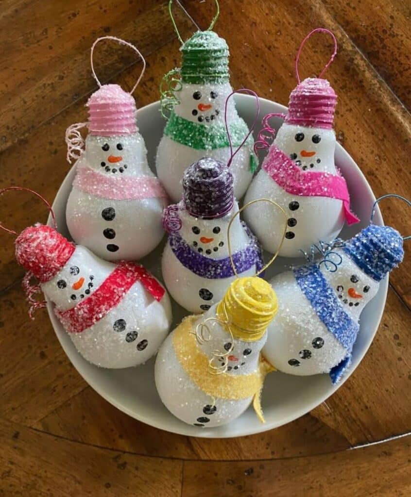 433fda8ddd28257c86a2967be572b2e2 Crafty snowman ornaments made from repurposed light bulbs, decorated with colorful hats and scarves, in a dish on a wooden table. | Sky Rye Design Crafty snowman ornaments made from repurposed light bulbs, decorated with colorful hats and scarves, in a dish on a wooden table.