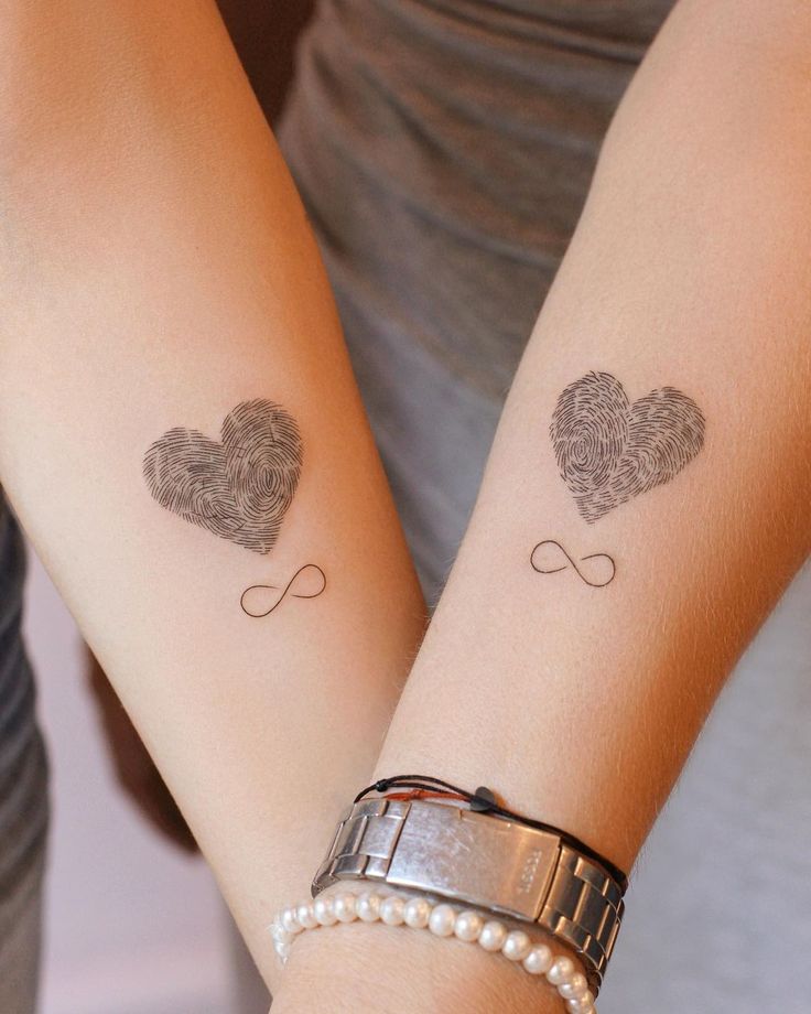 45+ Beautiful Infinity Tattoo Designs for Endless Love Two arms with fingerprint heart tattoos above infinity symbols, symbolizing eternal love. One wrist adorned with a watch and pearl bracelet. | Sky Rye Design Two arms with fingerprint heart tattoos above infinity symbols, symbolizing eternal love. One wrist adorned with a watch and pearl bracelet.