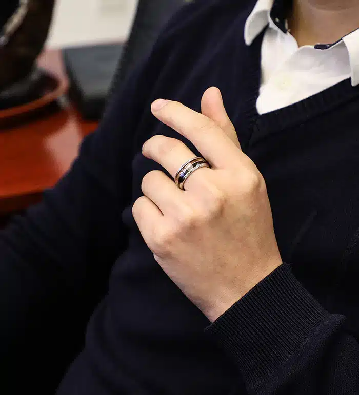 453838775690 Person wearing a black tungsten ring, seated in an office chair, demonstrating modern and stylish jewelry fashion. | Sky Rye Design Person wearing a black tungsten ring, seated in an office chair, demonstrating modern and stylish jewelry fashion.
