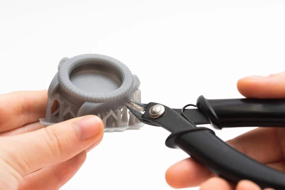 Hands using clippers to trim a 3D-printed model, focusing on detail and precision.