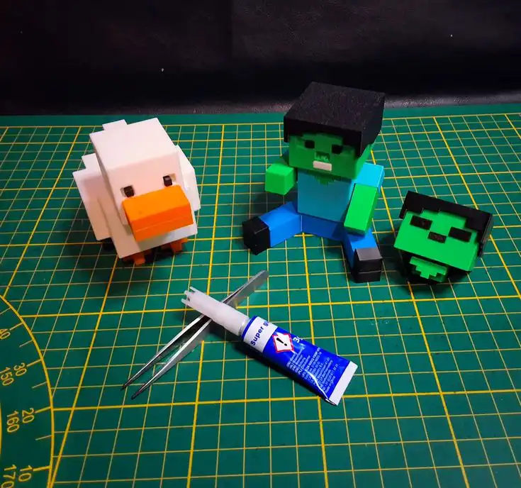 _ 5 Crafting figures of a duck and blocky characters with tools on a green cutting mat for DIY projects. | Sky Rye Design Crafting figures of a duck and blocky characters with tools on a green cutting mat for DIY projects.