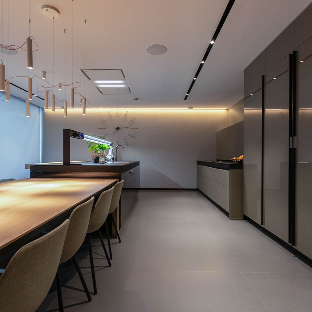 5abb299d88db6255dbd888767da9d1b9 Modern kitchen interior with sleek cabinets, dining area, and ambient lighting. Minimalist design featuring a clock and pendant lights. | Sky Rye Design Modern kitchen interior with sleek cabinets, dining area, and ambient lighting. Minimalist design featuring a clock and pendant lights.