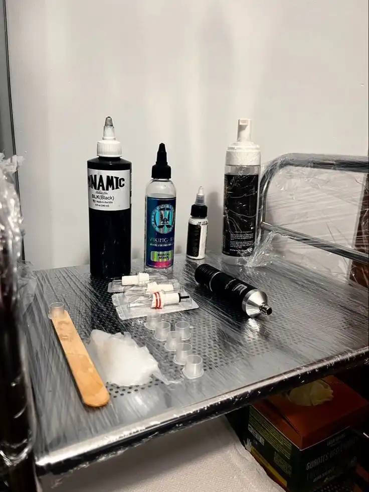 Tattoo artist's tools on a metal tray, including ink bottles, caps, and applicators. Ready for professional tattooing.