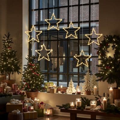 6-Pack 12-Inch Hanging Starburst Christmas Lights 60 LED Battery-Operated Cozy Christmas scene with glowing star lights, decorated trees, wreaths, and wrapped gifts by a window, creating a festive holiday atmosphere. | Sky Rye Design Cozy Christmas scene with glowing star lights, decorated trees, wreaths, and wrapped gifts by a window, creating a festive holiday atmosphere.