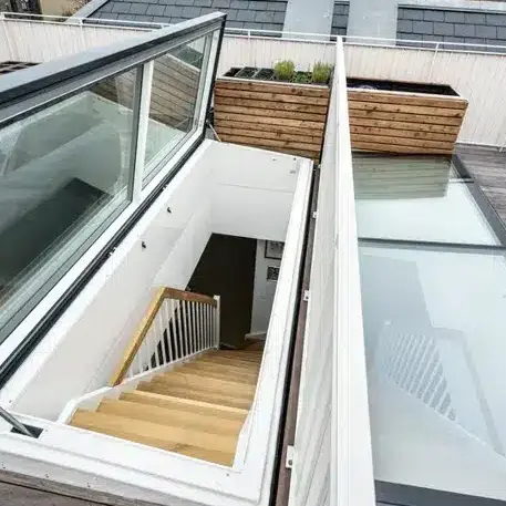 Modern rooftop access with glass doors, wooden stairs, and planter box. Ideal for urban homes seeking stylish outdoor entrances.