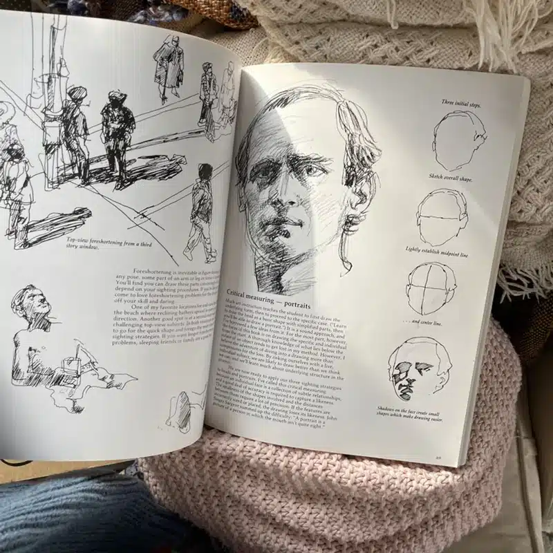 6e07d6f6-af7a-4474-8f98-9bc4598048fc Open sketchbook showing portrait drawing techniques with detailed illustrations and shadowing guides, lying on a textured surface. | Sky Rye Design Open sketchbook showing portrait drawing techniques with detailed illustrations and shadowing guides, lying on a textured surface.