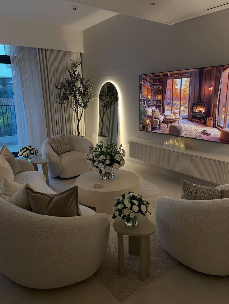 _ 7 Cozy living room with elegant beige sofas, round tables, floral arrangements, large TV, and soft lighting for a warm ambiance. | Sky Rye Design Cozy living room with elegant beige sofas, round tables, floral arrangements, large TV, and soft lighting for a warm ambiance.