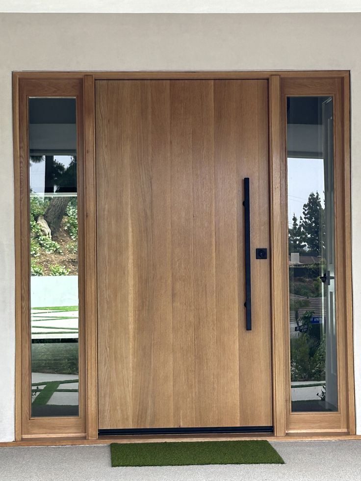 _ 8 Modern wooden front door with sleek black handle, flanked by vertical glass panels, enhancing the entrance with natural light and style. | Sky Rye Design Modern wooden front door with sleek black handle, flanked by vertical glass panels, enhancing the entrance with natural light and style.