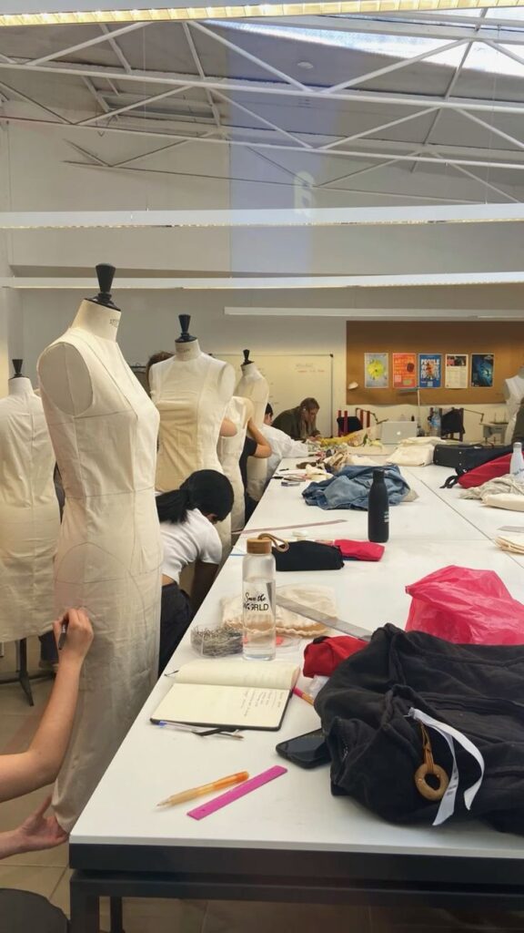 _ 8 Fashion design students working on dress forms in a creative classroom setting, surrounded by sewing materials and tools. | Sky Rye Design Fashion design students working on dress forms in a creative classroom setting, surrounded by sewing materials and tools.