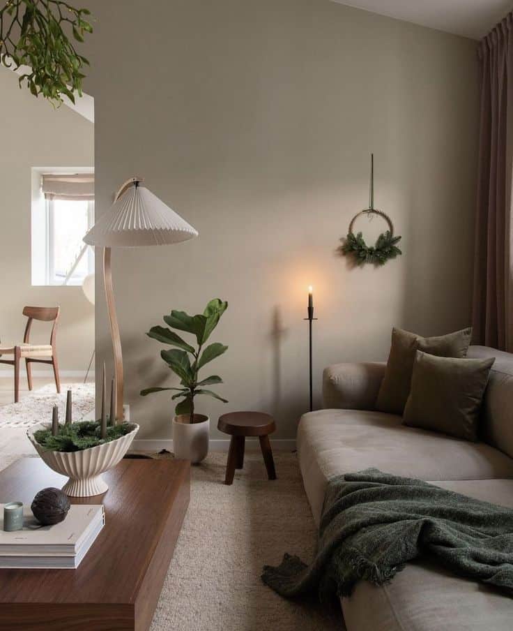 Minimalist living room with beige couch, wooden coffee table, indoor plants, and cozy lighting, creating a calm, inviting atmosphere.