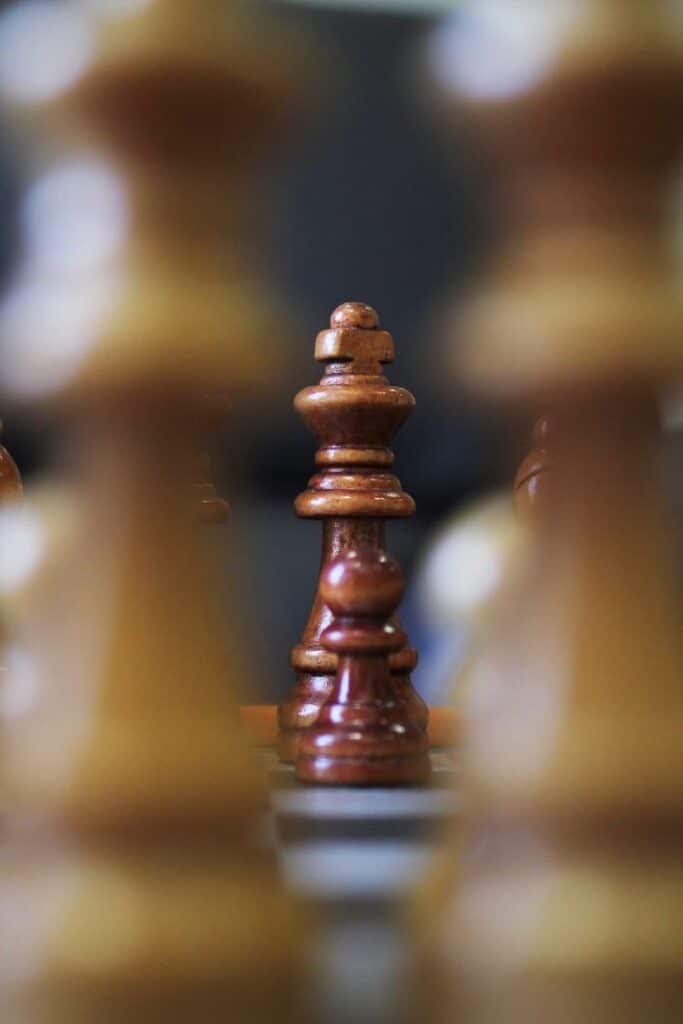 _ 9 Chess pieces on a board with a focused wooden king surrounded by blurred pawns, symbolizing strategy and leadership in the game. | Sky Rye Design Chess pieces on a board with a focused wooden king surrounded by blurred pawns, symbolizing strategy and leadership in the game.