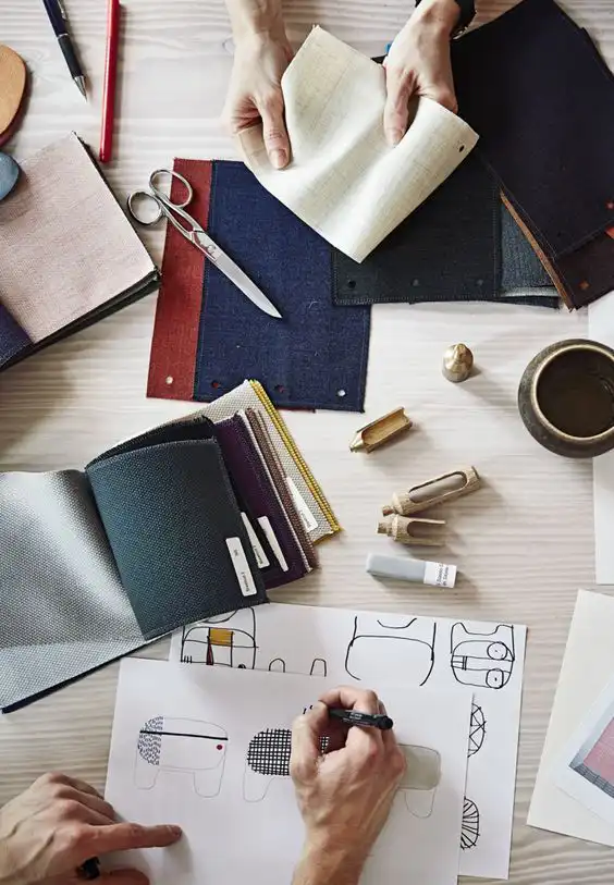Designer working on sketches and fabric samples, surrounded by creative tools on a desk. Ideal workspace for textile and design inspiration.