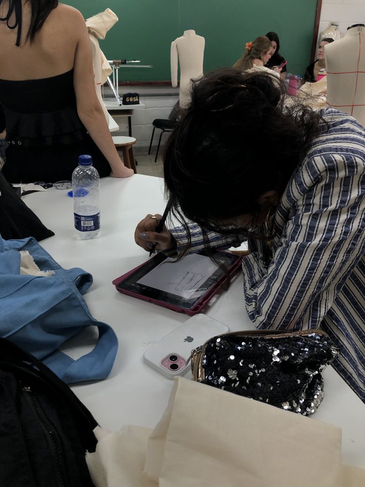 Student sketching on a tablet in a fashion design class, surrounded by mannequins and design tools, focused and creative atmosphere.