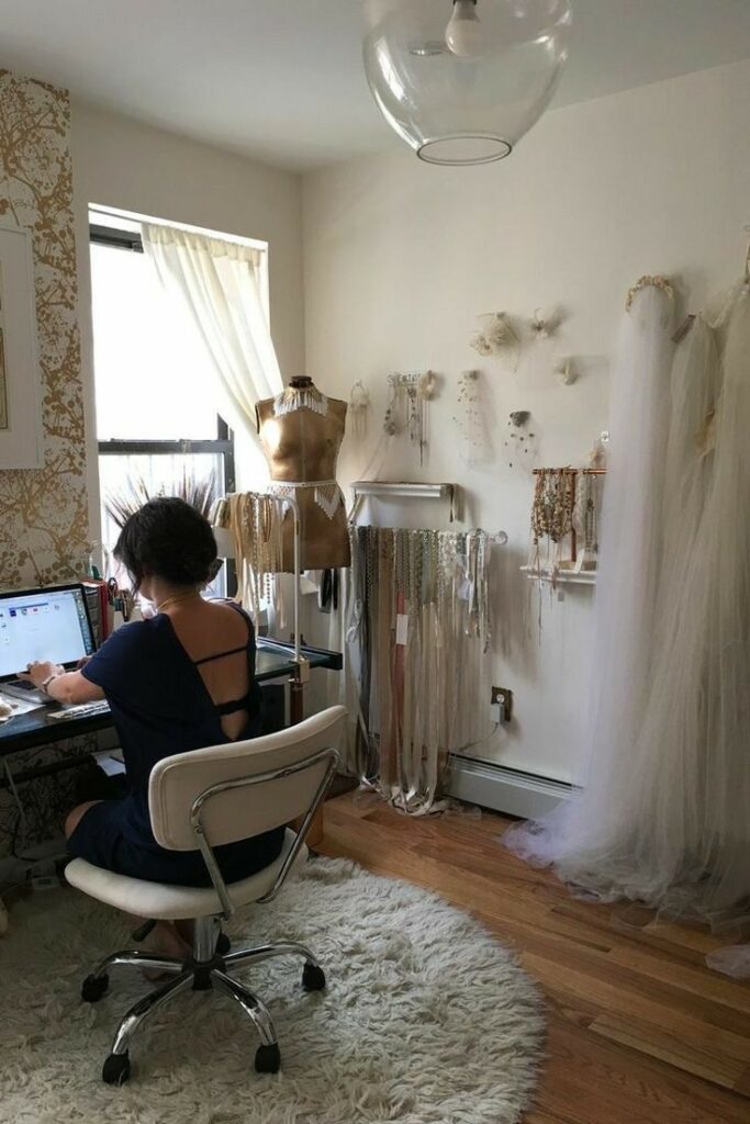 _ 9 Designer working at a desk in a stylish home studio with mannequins, lace, and textiles hanging on the walls. Cozy and creative workspace. | Sky Rye Design Designer working at a desk in a stylish home studio with mannequins, lace, and textiles hanging on the walls. Cozy and creative workspace.