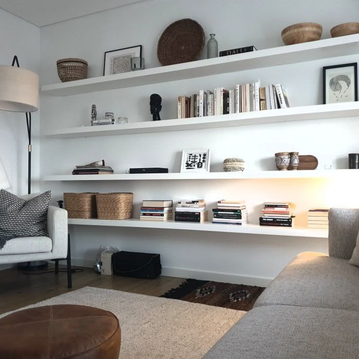 Modern living room with minimalist shelves, books, baskets, and stylish decor elements. Cozy armchair and neutral tones enhance the ambiance.