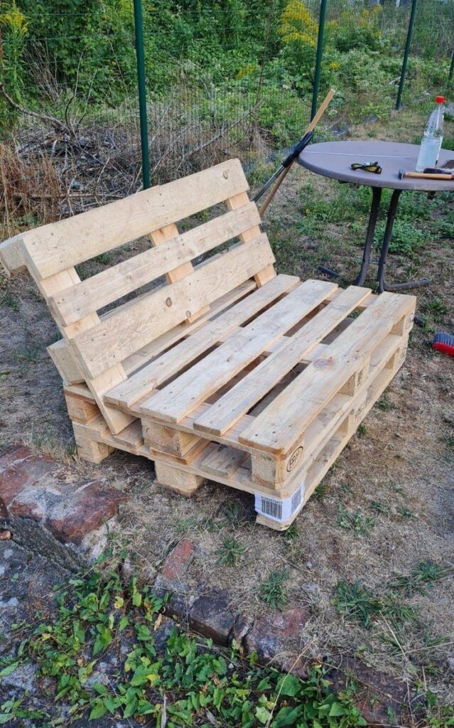 9a6a6f3d4e6602086e9a1a91fa7412b2 DIY wooden pallet bench in a garden setting, next to a small round table with tools and a drink bottle. | Sky Rye Design DIY wooden pallet bench in a garden setting, next to a small round table with tools and a drink bottle.