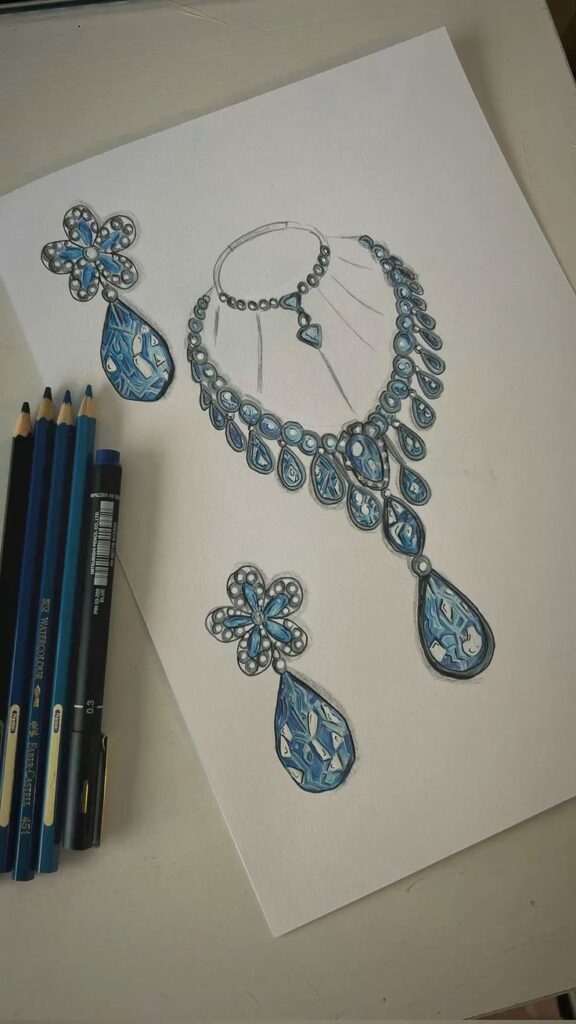 Sketch of an elegant jewelry set with blue gemstones, including a necklace and earrings, next to blue pencils.