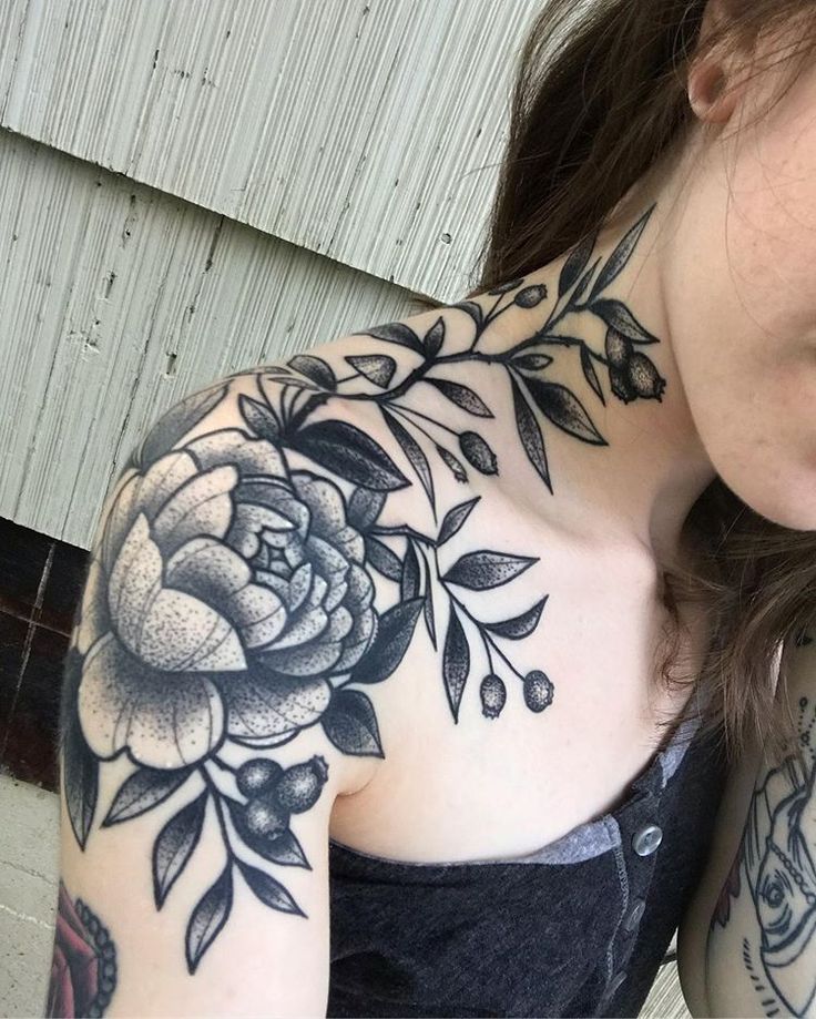 Black and gray floral tattoo on woman's shoulder and neck, showcasing detailed peony and leaves design.