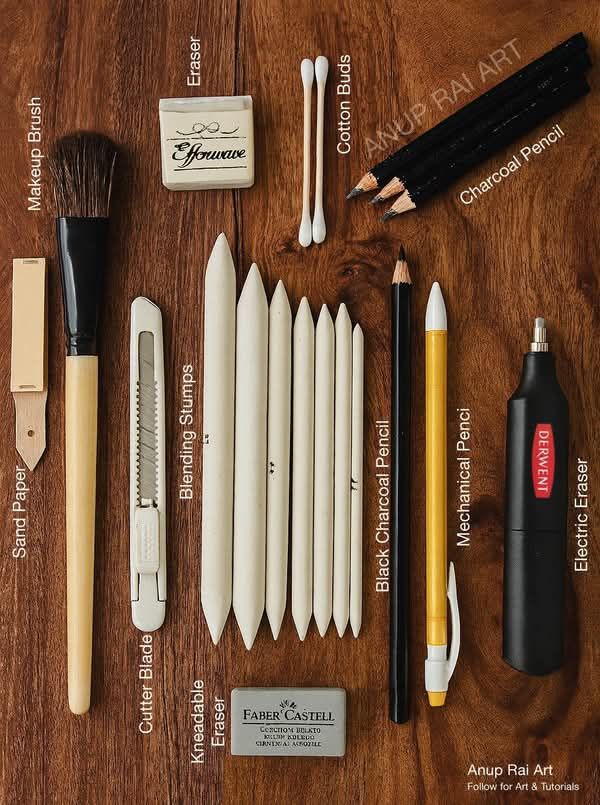 Art supplies on a wooden table including blending stumps, charcoal pencil, mechanical pencil, kneadable eraser, and cutter blade.