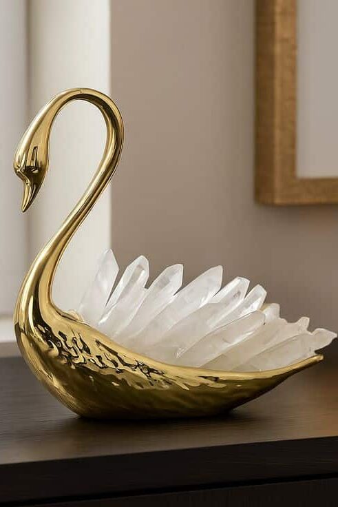Aviara Swan Decorative Object with Sculptural Crystal Accents - Modern Artistic Centerpiece for Elegant Home Decor_ Gold swan sculpture with crystal feathers on a dark wood surface near a window. Elegant home decor with artistic design. | Sky Rye Design Gold swan sculpture with crystal feathers on a dark wood surface near a window. Elegant home decor with artistic design.