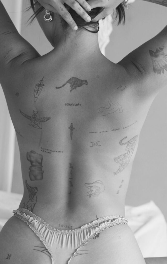 Back Tattoo 1 Person's back with diverse tattoos including animals, symbols, and phrases. Black and white image showcasing expressive art and style. | Sky Rye Design Person's back with diverse tattoos including animals, symbols, and phrases. Black and white image showcasing expressive art and style.