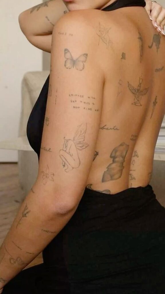 Back Tattoo 2 Person's back displaying various black ink tattoos, including a butterfly and a phrase, highlighting intricate body art design. | Sky Rye Design Person's back displaying various black ink tattoos, including a butterfly and a phrase, highlighting intricate body art design.