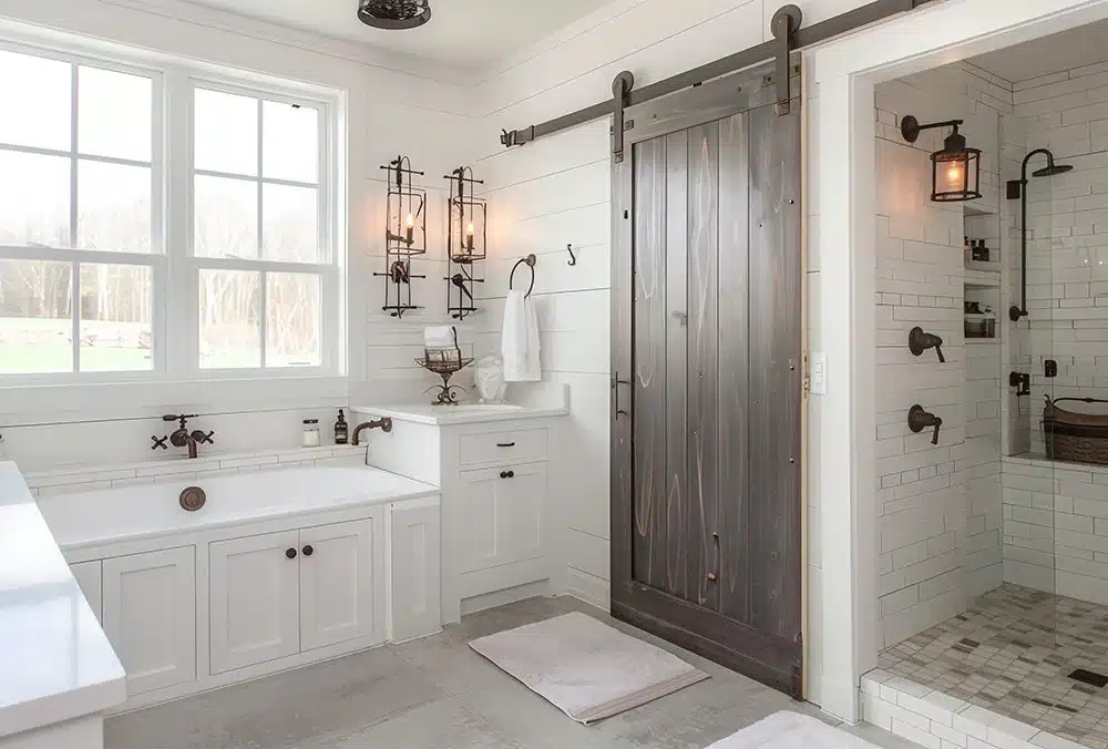 Bathroom-Collection-Lifestyle_image6_29e1d2c4-1d69-47db-915c-dd73ac3719c7 Modern farmhouse bathroom with a soaking tub, sliding barn door, and white subway tiles. Natural light from large window. | Sky Rye Design Modern farmhouse bathroom with a soaking tub, sliding barn door, and white subway tiles. Natural light from large window.