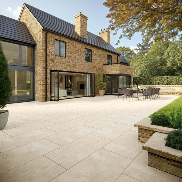 Beigeivory-stone-effect-porcelain-outdoor-slab-tile-patio-area-2300-1 Modern brick house with spacious patio, outdoor dining, and lush greenery, showcasing luxurious outdoor living and architectural elegance. | Sky Rye Design Modern brick house with spacious patio, outdoor dining, and lush greenery, showcasing luxurious outdoor living and architectural elegance.